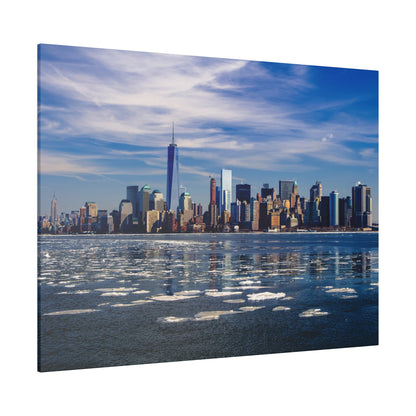 Panoramic view of the New York City skyline along the water, with floating ice and a blue sky.