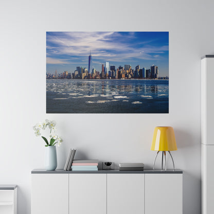Framed city skyline across a calm river with floating ice, blue sky, and tall skyscrapers.