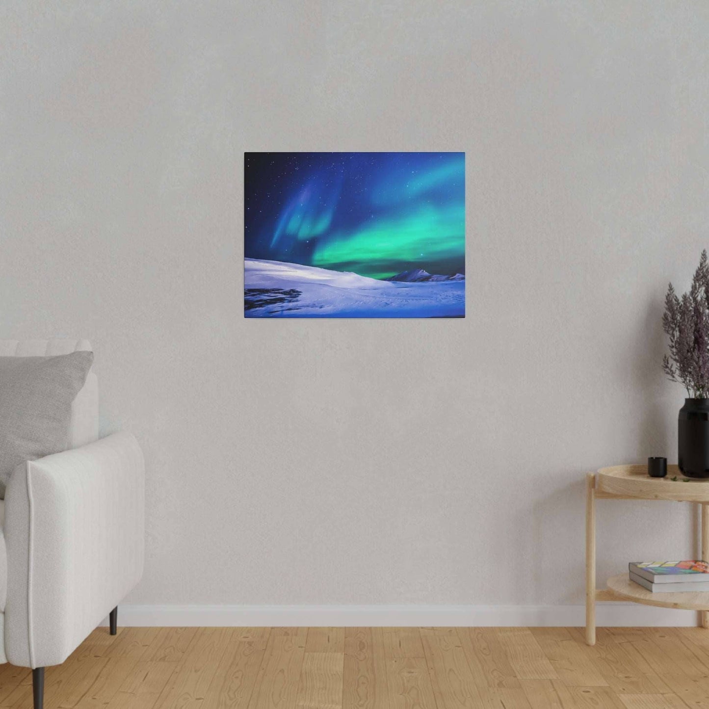 Canvas art on a light gray wall showing a vivid green and blue aurora over snowy hills.