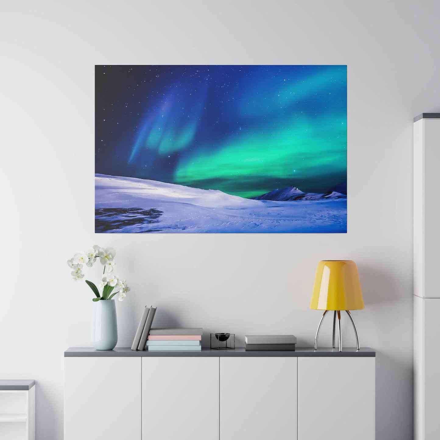 Large wall art depicting a snowy landscape under green and blue northern lights above a minimalist white console.