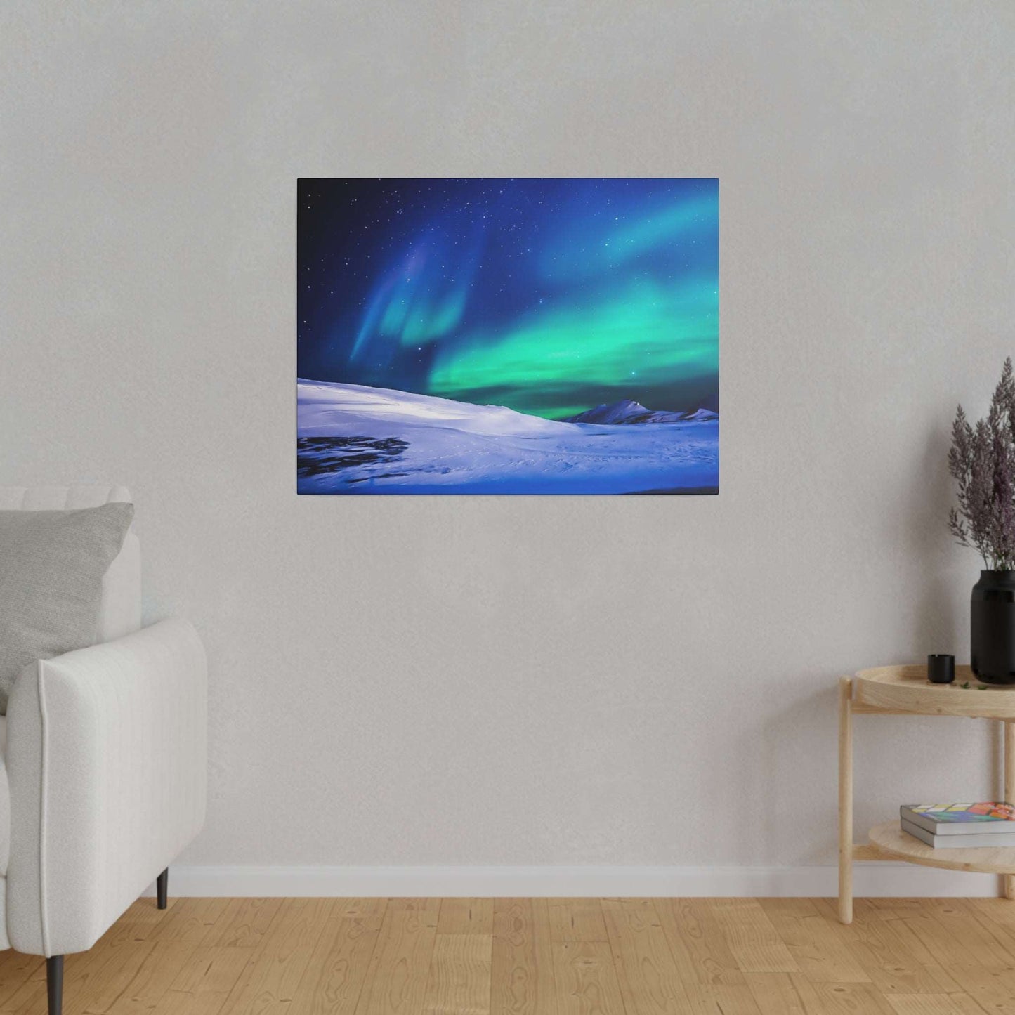 Canvas art showing green and blue northern lights over a snowy landscape, mounted on a light gray wall.
