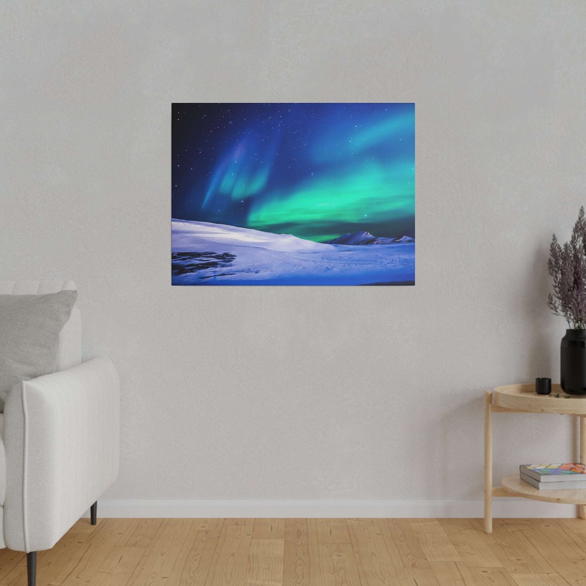 Canvas art showing green and blue northern lights over a snowy landscape, mounted on a light gray wall.