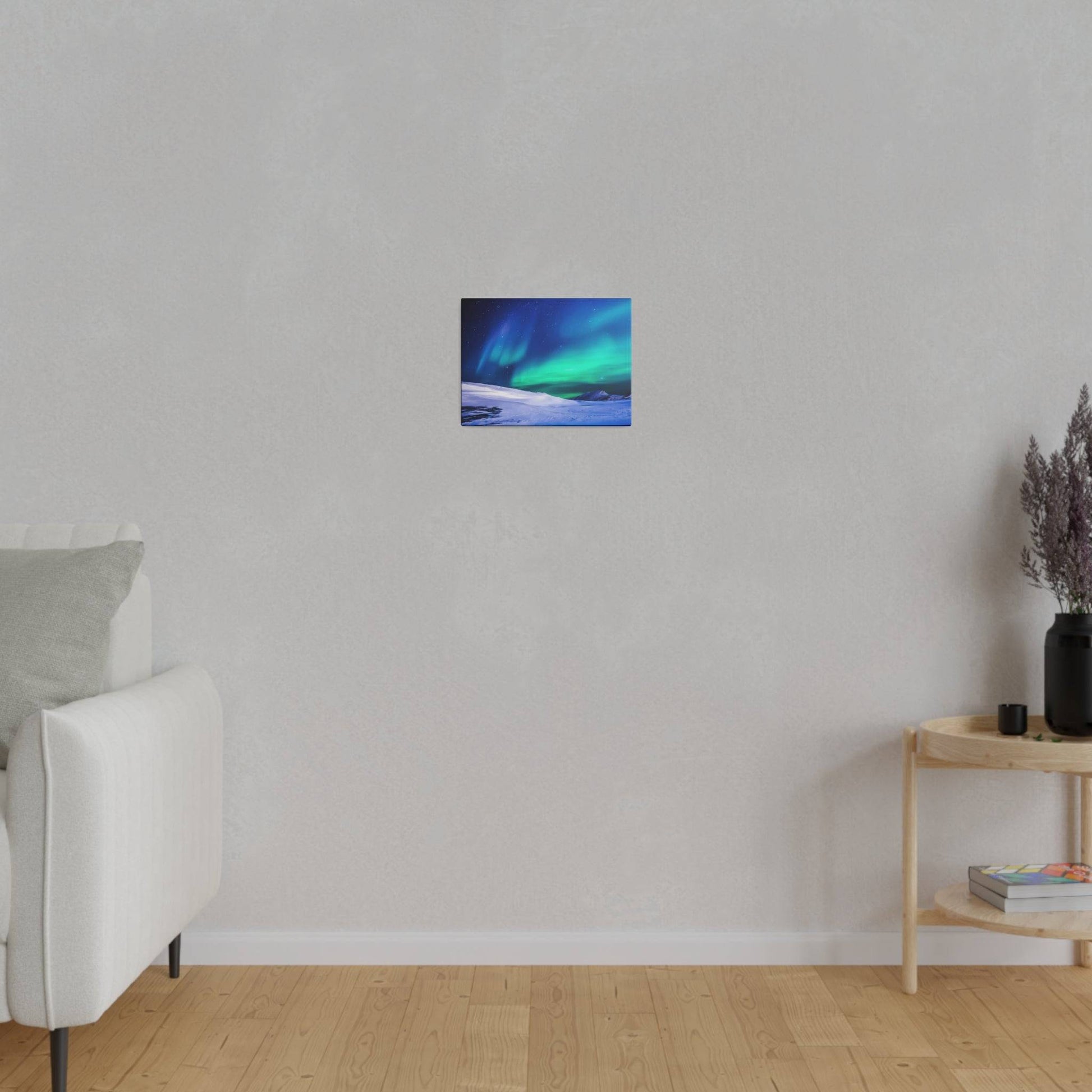 Small rectangular painting of blue and green northern lights over snow, hung on a light gray wall above a wooden floor.