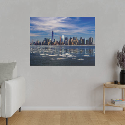 New York City skyline across a partially frozen river with ice floes under a blue sky.