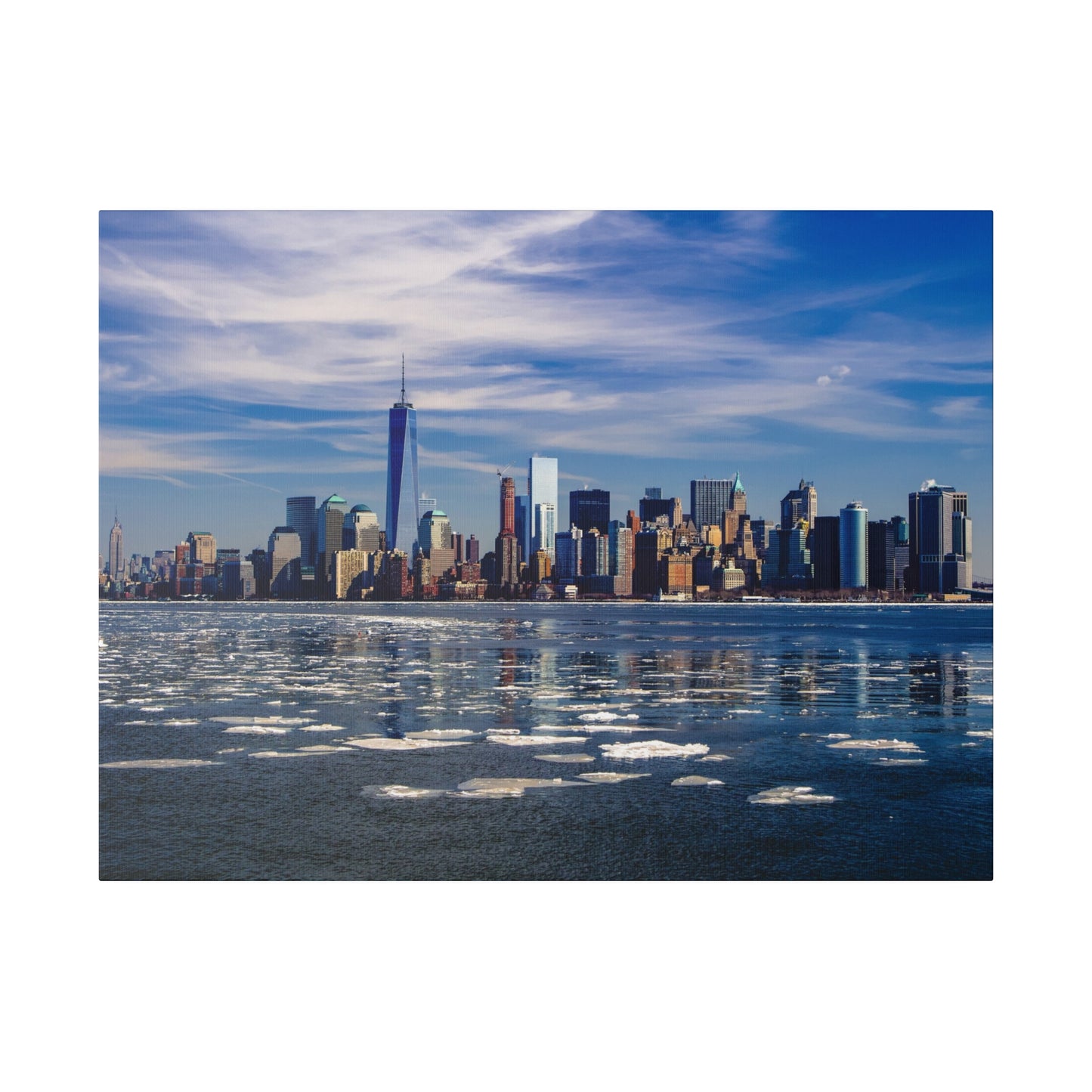 New York City’s skyscrapers standing tall under a blue sky, reflected in the calm waters of the river.