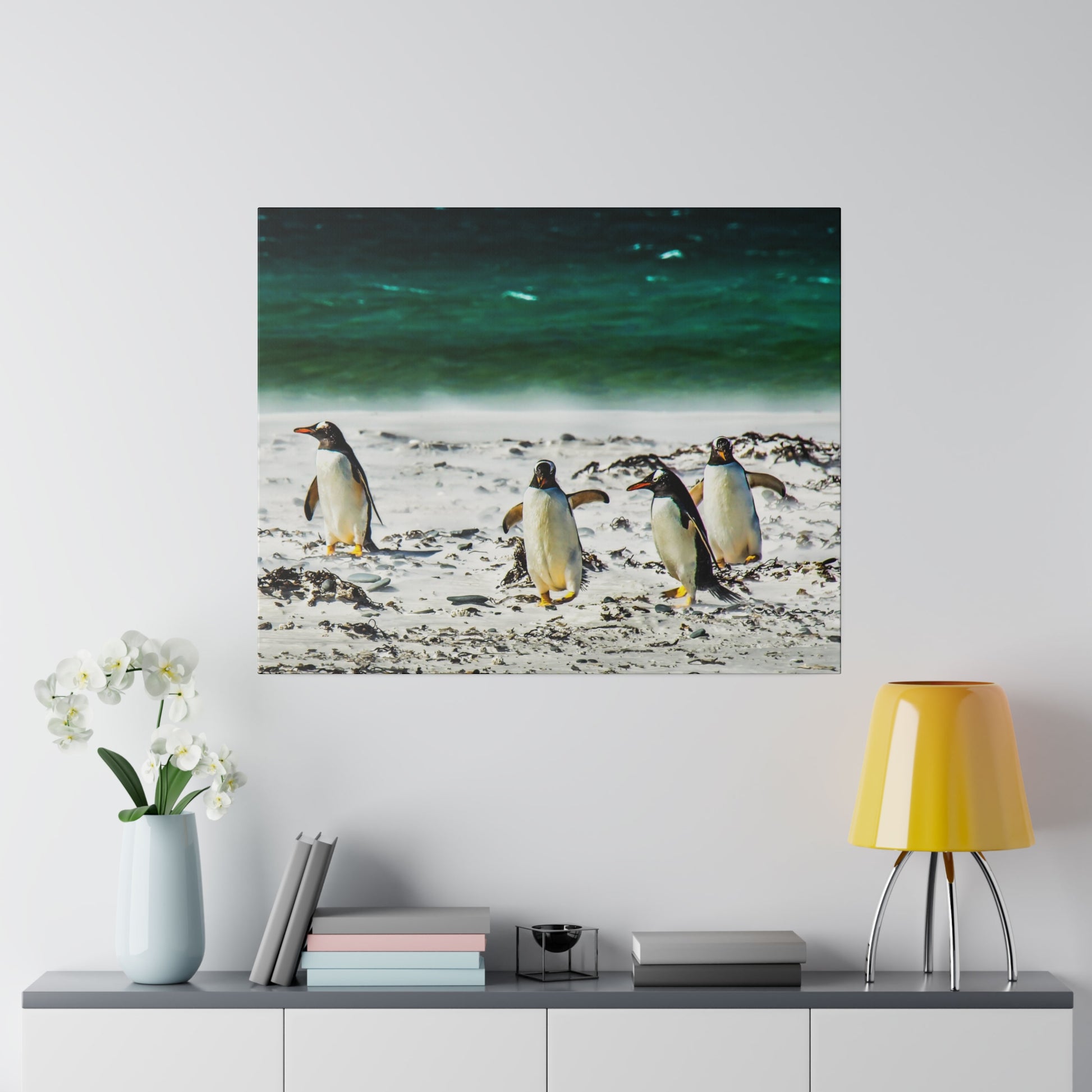 Penguins at the edge of the ocean, walking on a sandy beach with the green-blue sea behind them. The peaceful scene showcases the beauty of their environment.