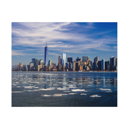 Panoramic view of the Manhattan skyline across a partly frozen river, with One World Trade Center and tall glass buildings under a blue sky.