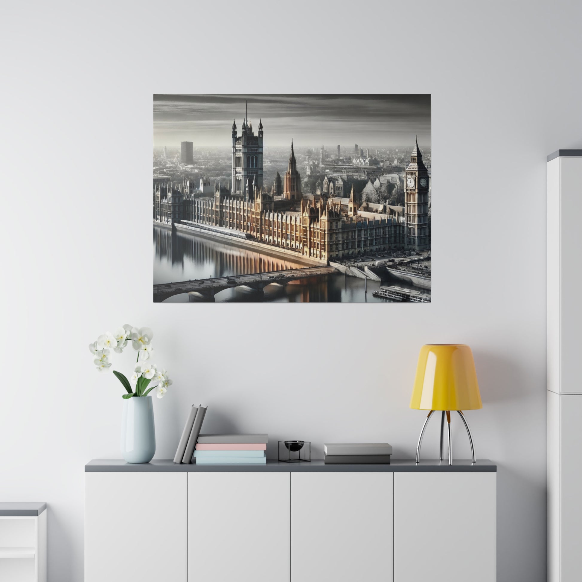Framed grayscale cityscape print of the Palace of Westminster with Big Ben, hung above a white sideboard with a yellow lamp and white