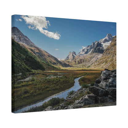 Mountain valley with a winding river, snow-capped peaks, rocky foreground, and clear blue sky.