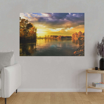 A riverside scene at sunset: calm water reflects warm golden hues as autumn trees line both banks.
