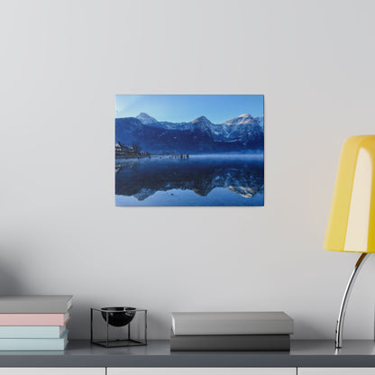 Blue-toned mountain landscape photo on a wall: snow-capped peaks mirrored in a calm lake.
