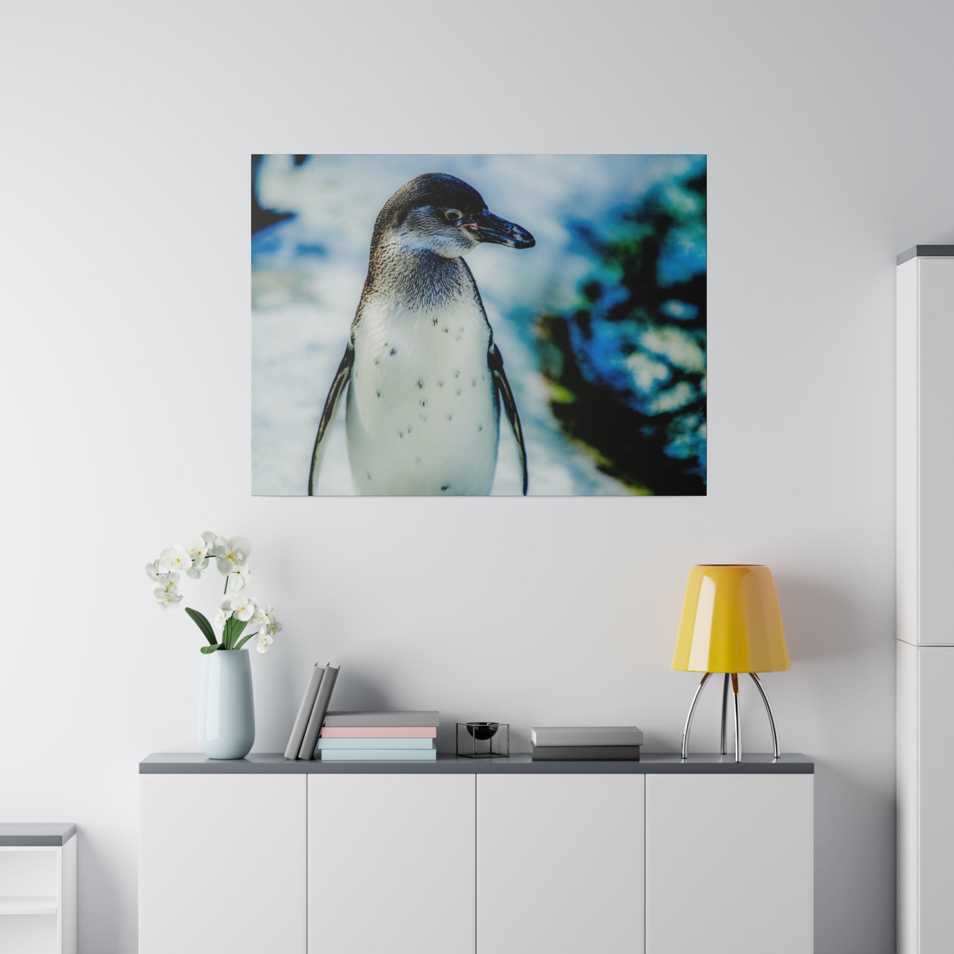 A penguin standing in front of an ice and snow background, with blue tones. The close-up image highlights the penguin’s features and the wintry setting.