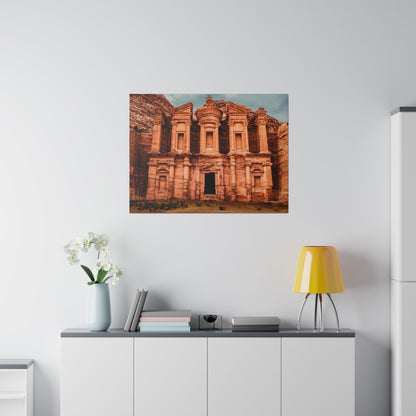 A large photograph of Petra's Treasury facade carved from pinkish-orange stone, mounted on a white wall.