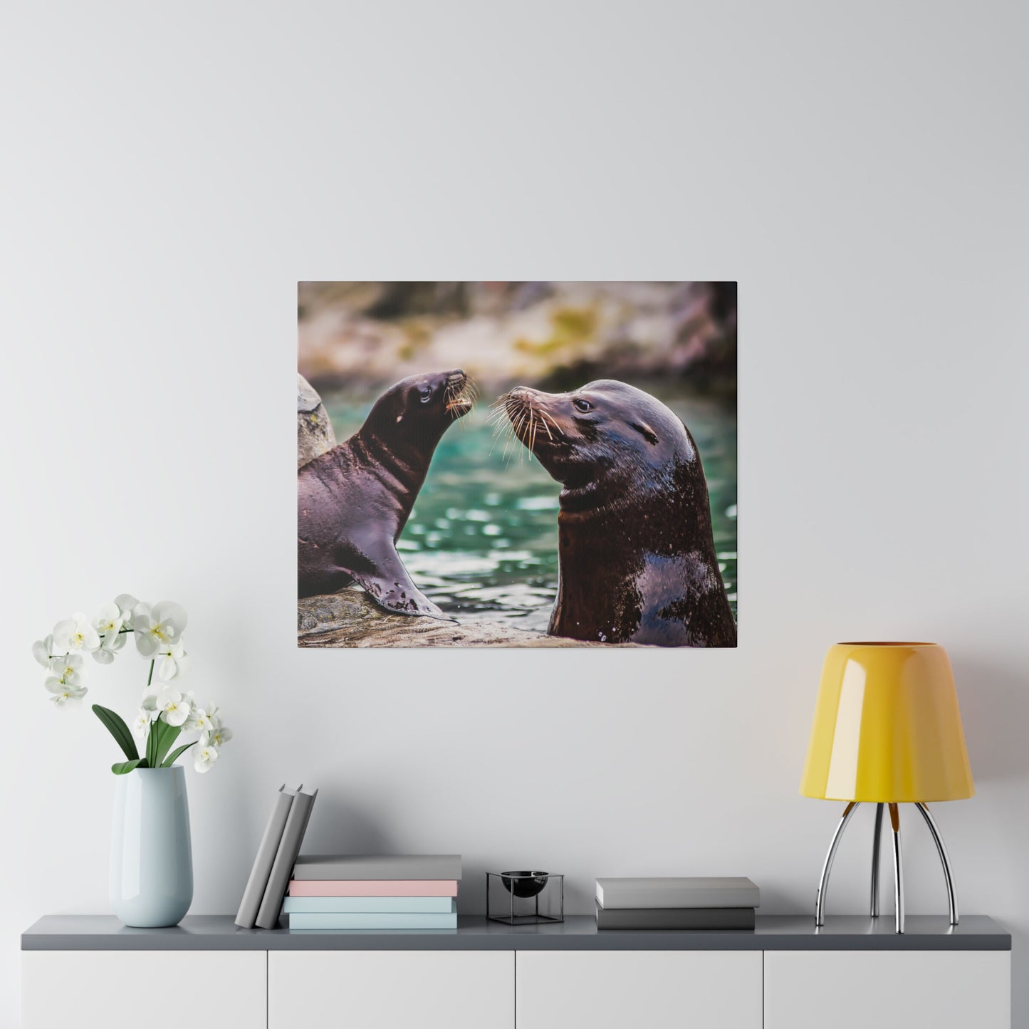 Two playful sea lions interacting by the water's edge. The scene captures their curiosity and social behavior, highlighting their whiskers and smooth fur.