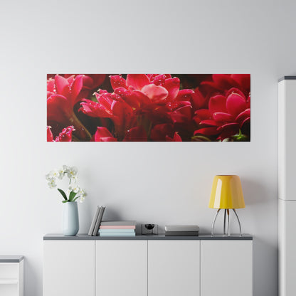 Rectangular wall art of red flowers hangs above a white cabinet, with a pale vase of white orchids and a yellow table lamp.