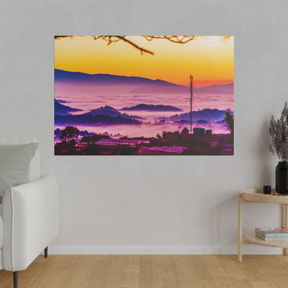 Colorful sunrise over a misty valley with purple hills, a small town, and a tall antenna tower.