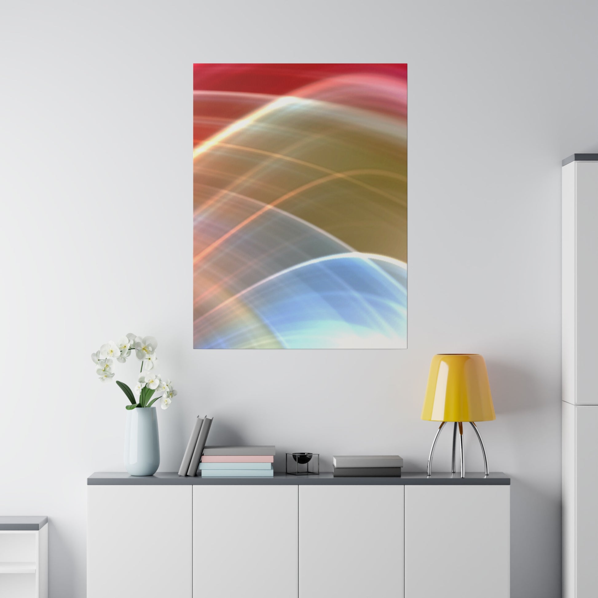 Abstract color poster with red, orange, blue, and yellow curved lines on a white wall above a white cabinet, beside a yellow lamp and vase