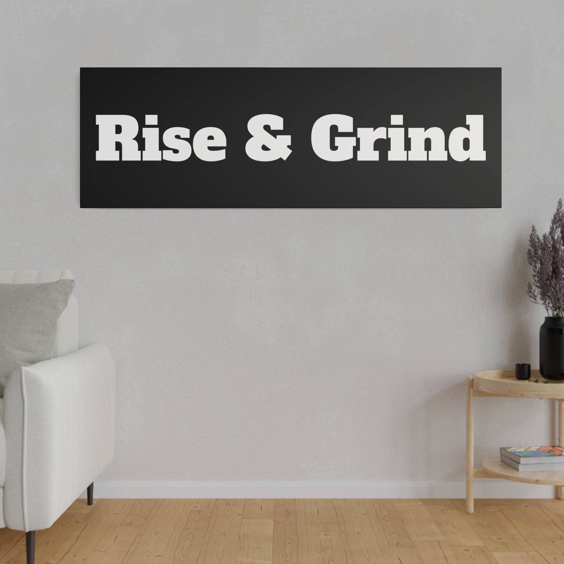 Living room wall with a black rectangular sign that says 'Rise & Grind' in white bold letters, white sofa to the left.