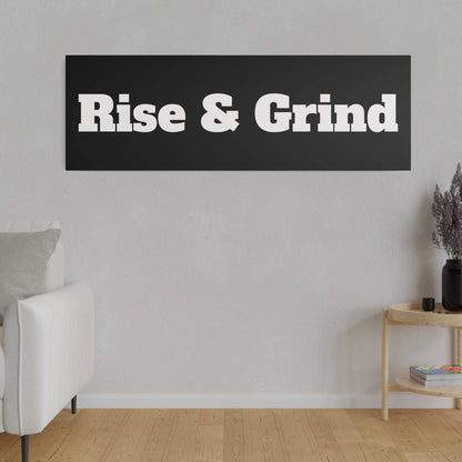 Living room wall with a black rectangular sign that says 'Rise & Grind' in white bold letters, white sofa to the left.