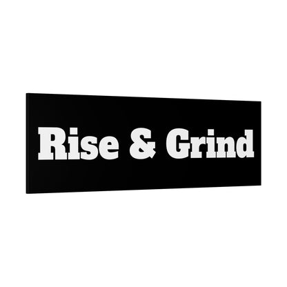 Black rectangular sign with large white text reading "Rise & Grind".