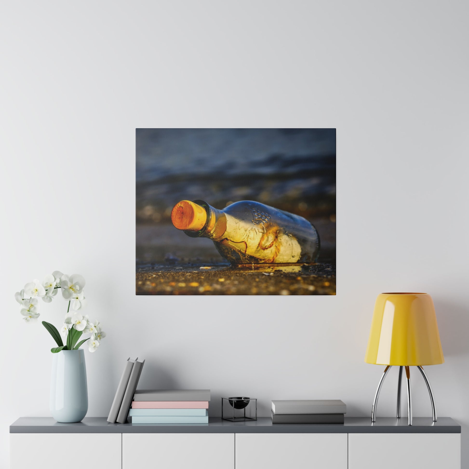 A transparent glass bottle with an orange cap lies on wet sand at the beach.