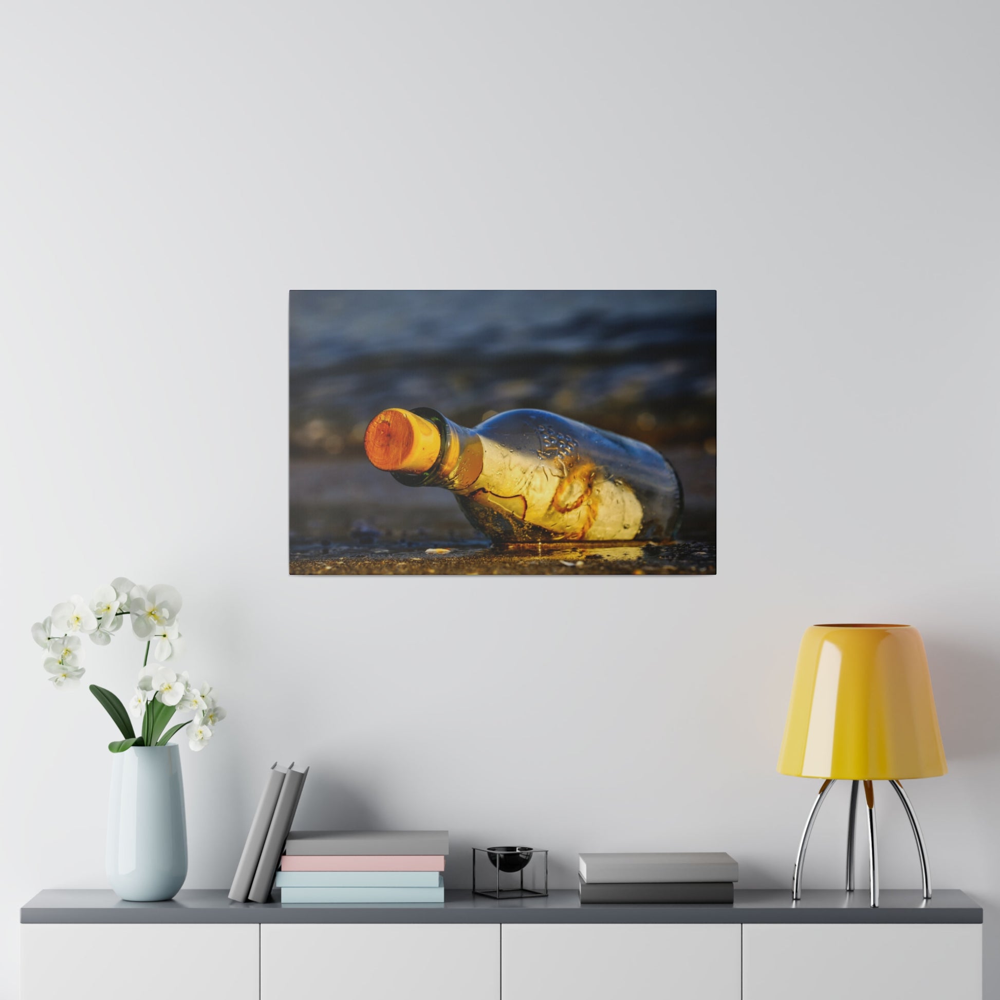 A glass bottle with an orange cap rests on wet sand at the edge of the shoreline.
