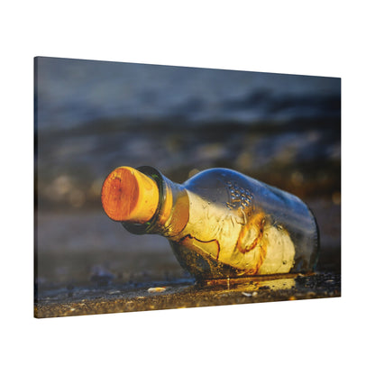 A clear glass bottle with an orange cork lies on wet sand near the shoreline, with water in the background.