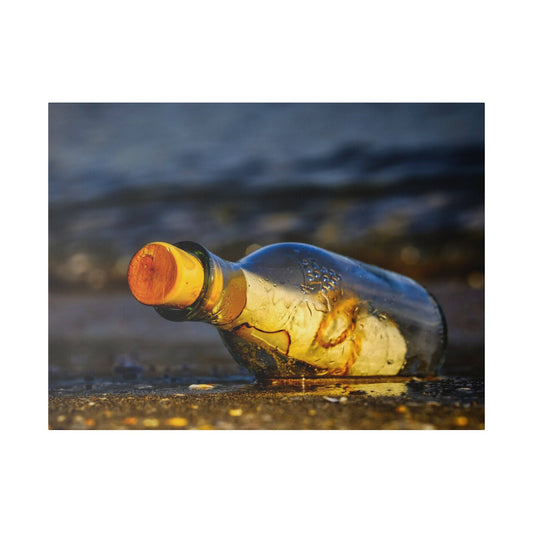 A clear glass bottle with an orange cap lies on wet sandy beach with droplets on its surface.