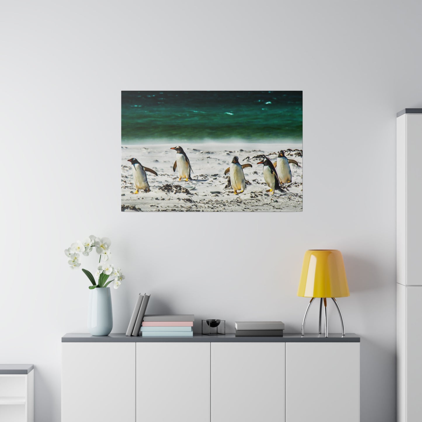 A parade of penguins walking by the seaside, with the green-blue ocean in the background. The beach scene is tranquil and picturesque.