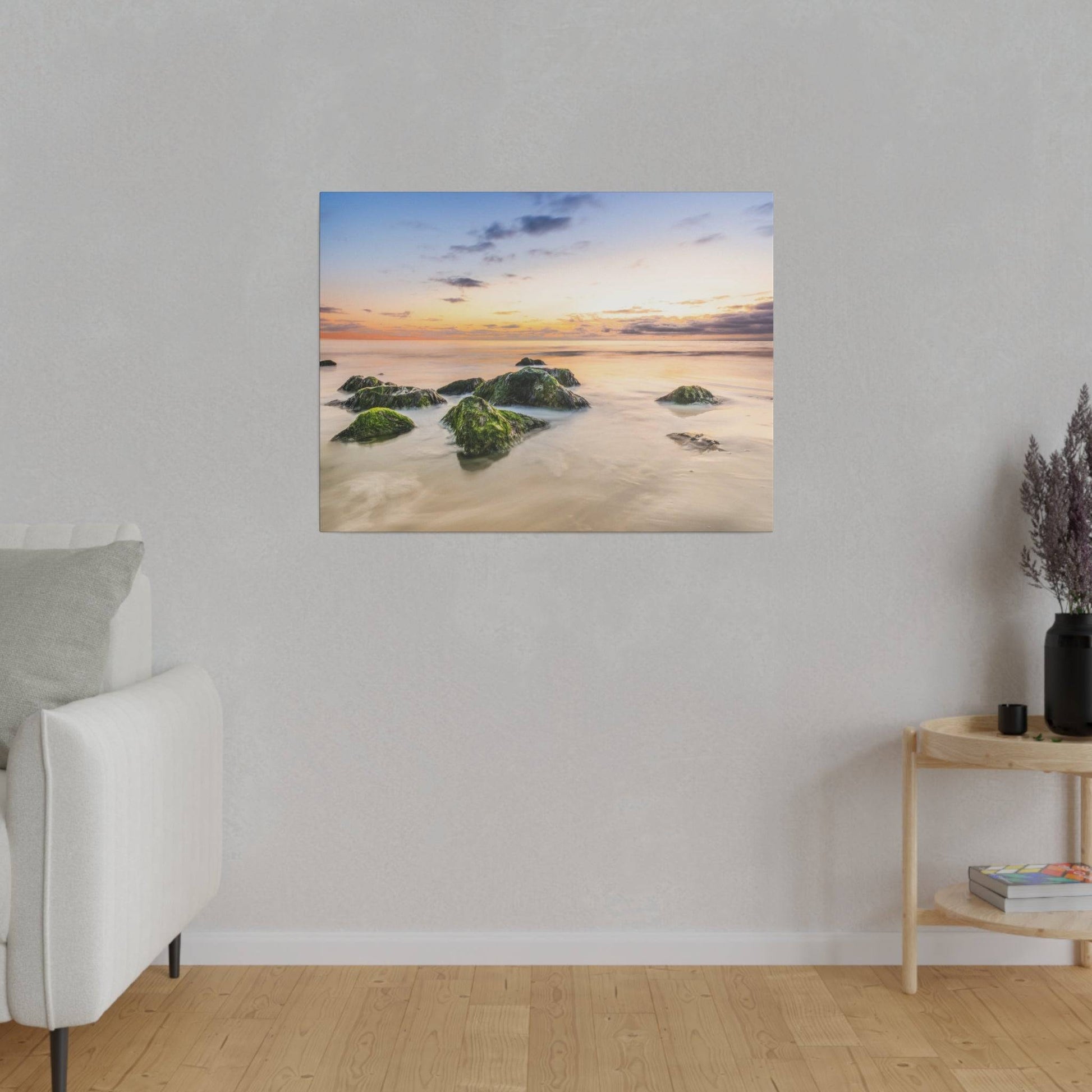 A white sofa on the left in a light gray living room, with a framed beach sunset painting on the wall.