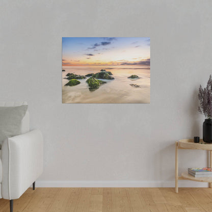A white sofa on the left in a light gray living room, with a framed beach sunset painting on the wall.