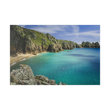 Rocky coastline with green cliffs, a small sandy beach, and turquoise sea under a blue sky.