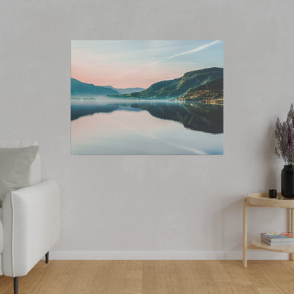 Framed landscape photo of a calm lake reflecting pastel sky and green mountains, hung on a light gray wall.