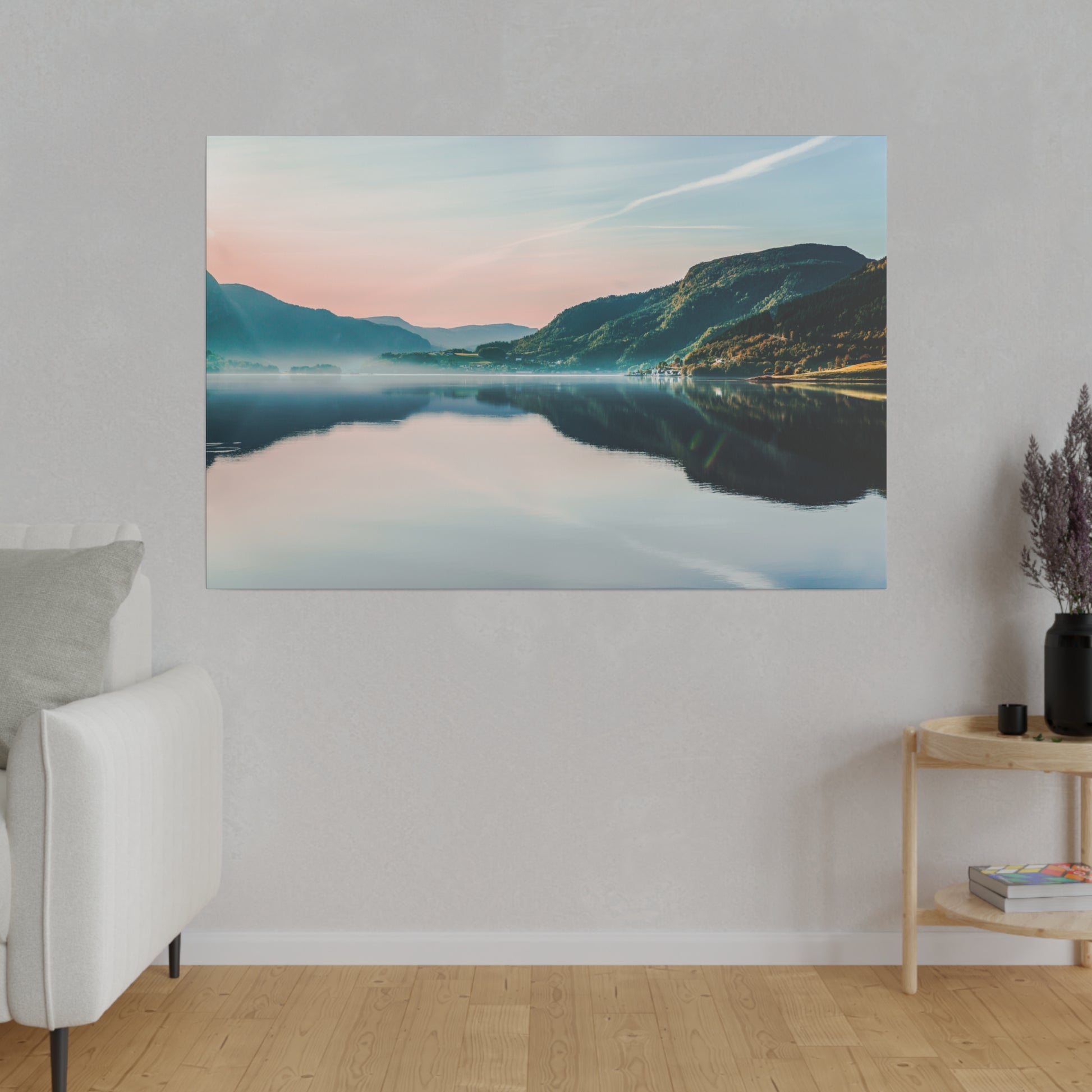 Landscape photograph of a tranquil lake with mountains and pastel sky, reflecting in calm water, hung on a gray living-room wall.