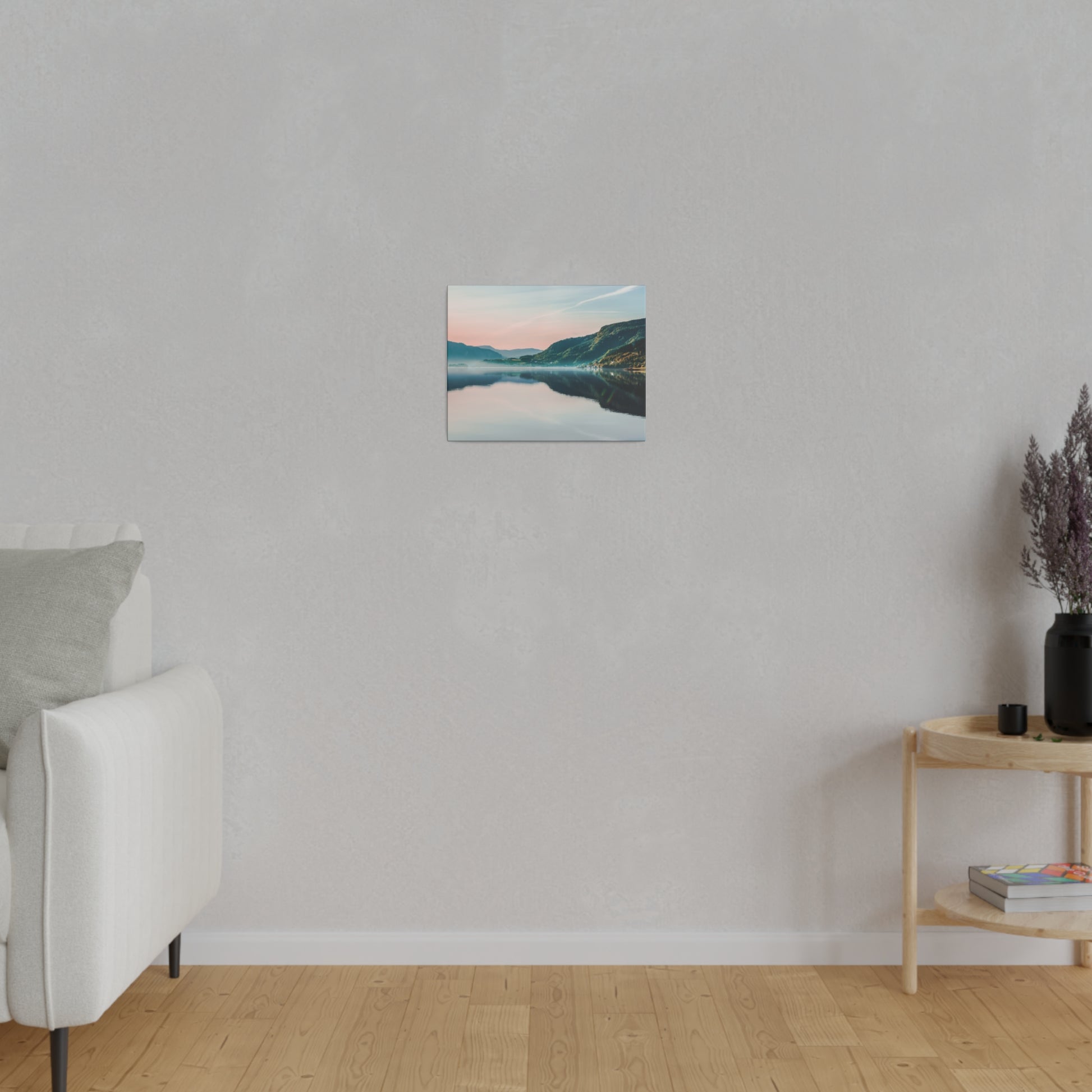 Small square landscape canvas of a lake and mountains hangs on a light gray textured wall in a minimalist living room.