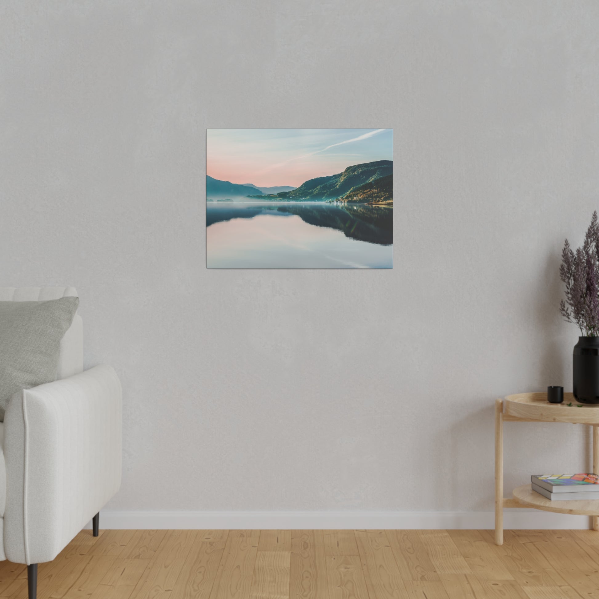 Framed landscape canvas of a tranquil lake and mountains in pastel pink and blue hues, hung on a light gray wall.
