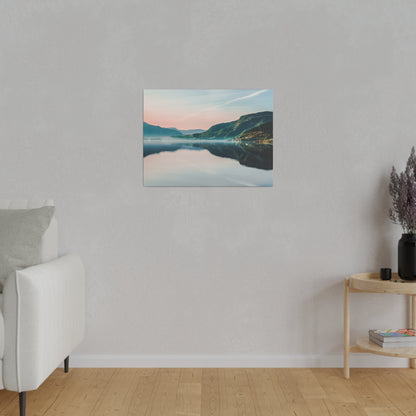 Framed landscape canvas of a tranquil lake and mountains in pastel pink and blue hues, hung on a light gray wall.