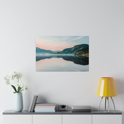 Framed landscape wall art depicting a calm lake and mountains at sunset, mounted above a console with a pale blue vase, books, and a