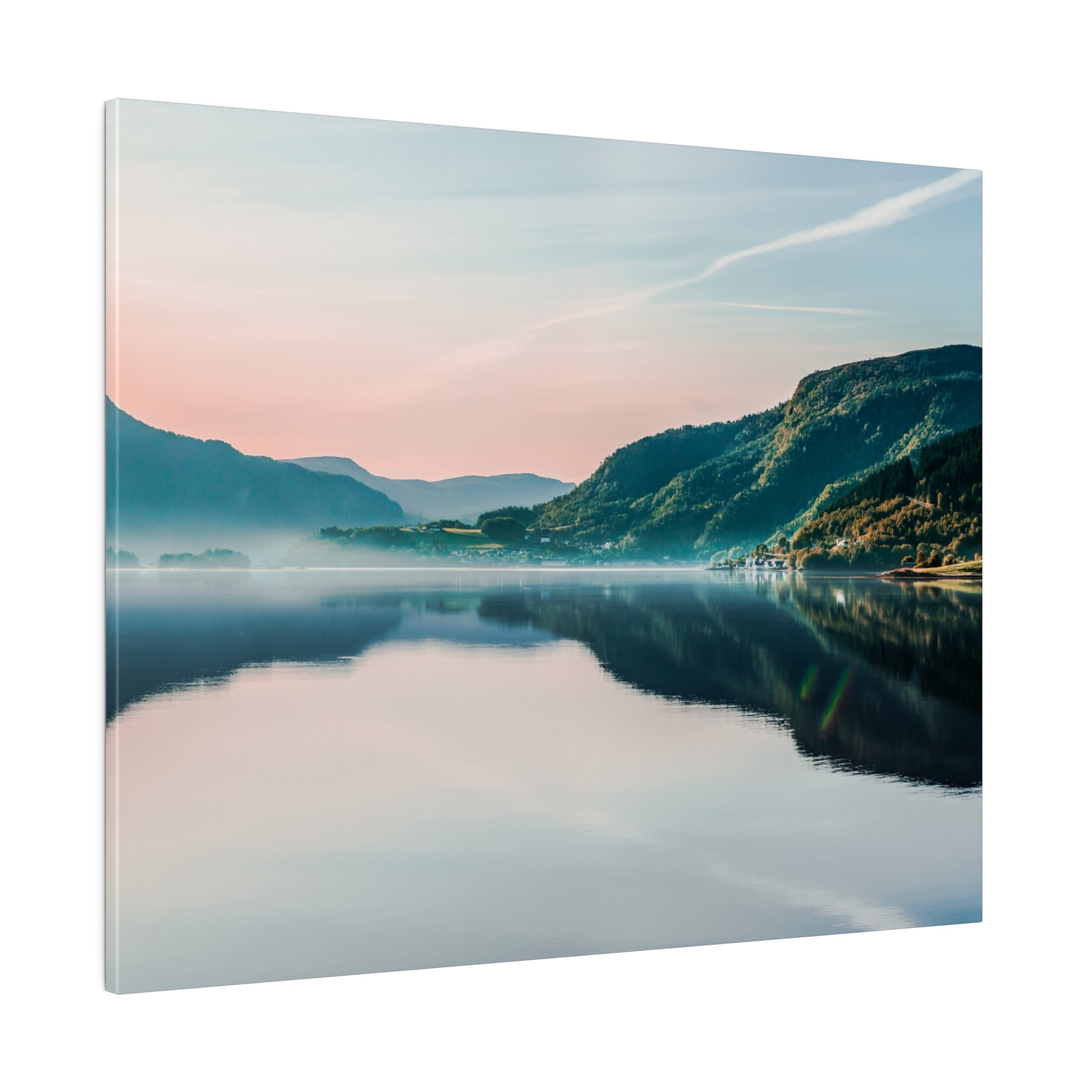 A calm lake mirrors green mountains and a pastel sky, with light mist along the shoreline.
