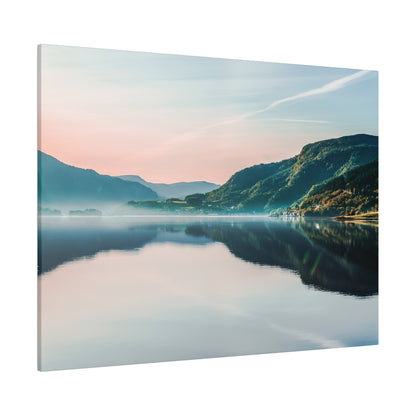 Landscape photograph of a calm lake reflecting mountains and a pastel sky at dawn, with mist along the shoreline.