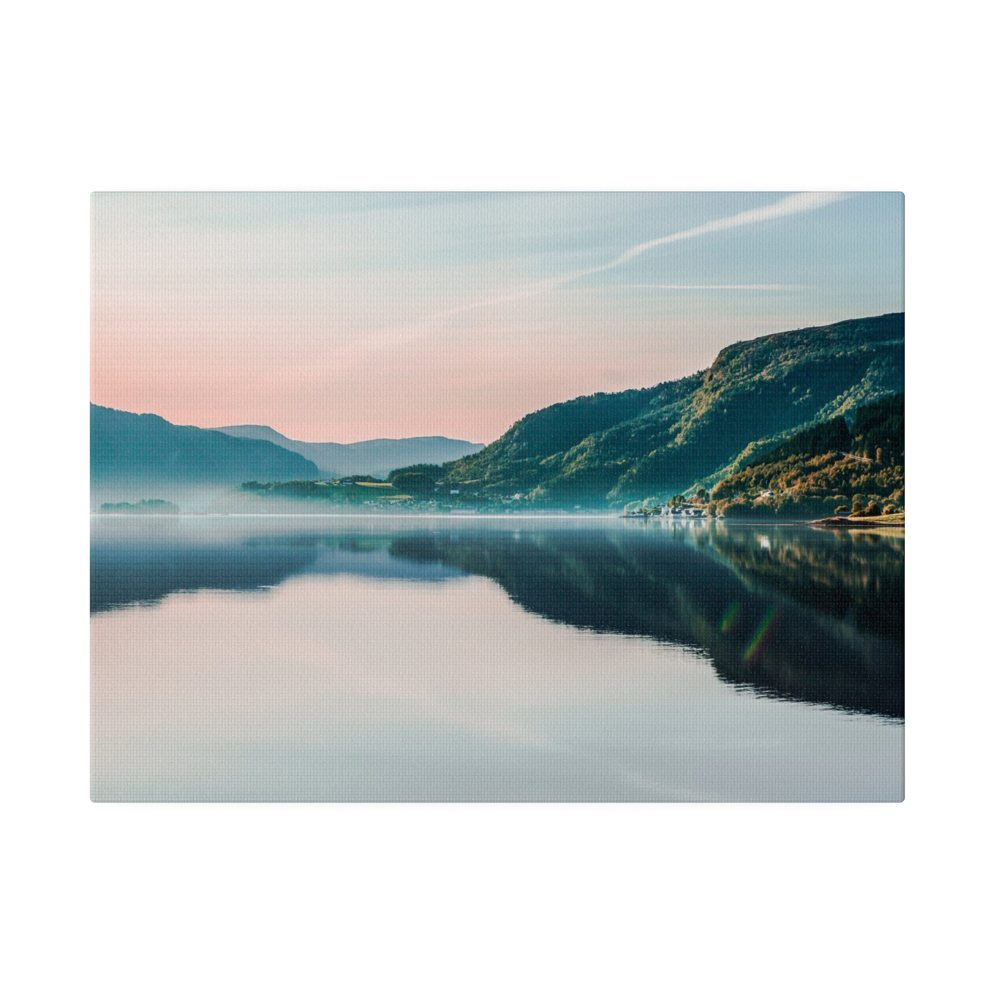 Calm lake reflecting pink and blue sky, with green mountains along the shoreline.