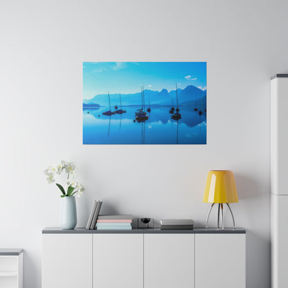 Blue-toned landscape painting of sailboats on calm water with mountains, hung above a white sideboard in a bright room.