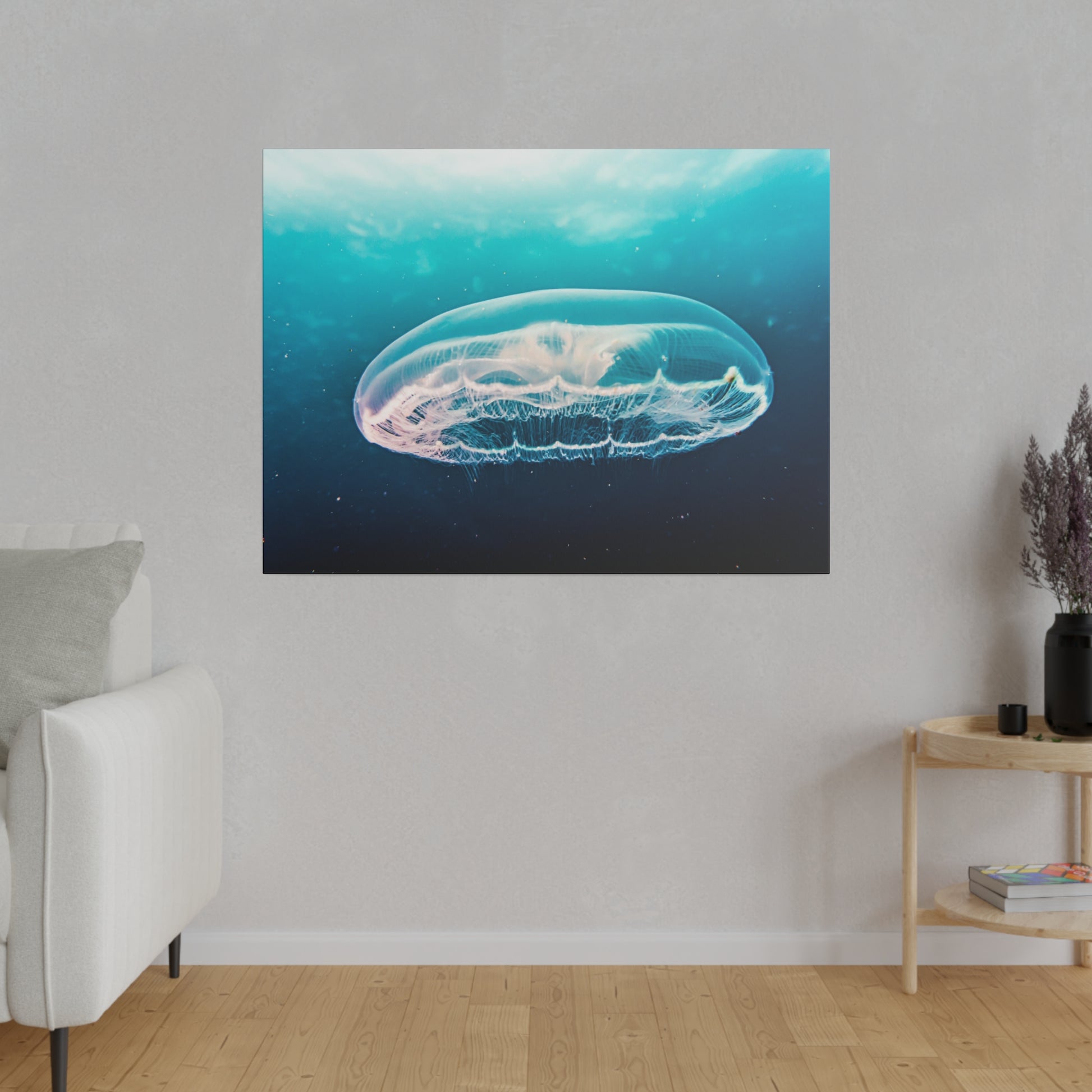 Square wall art depicting a translucent jellyfish in turquoise-blue ocean water, hung on a light gray wall.