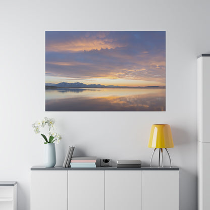 Wall art showing a calm lake at sunset with orange and purple clouds reflecting on the water.