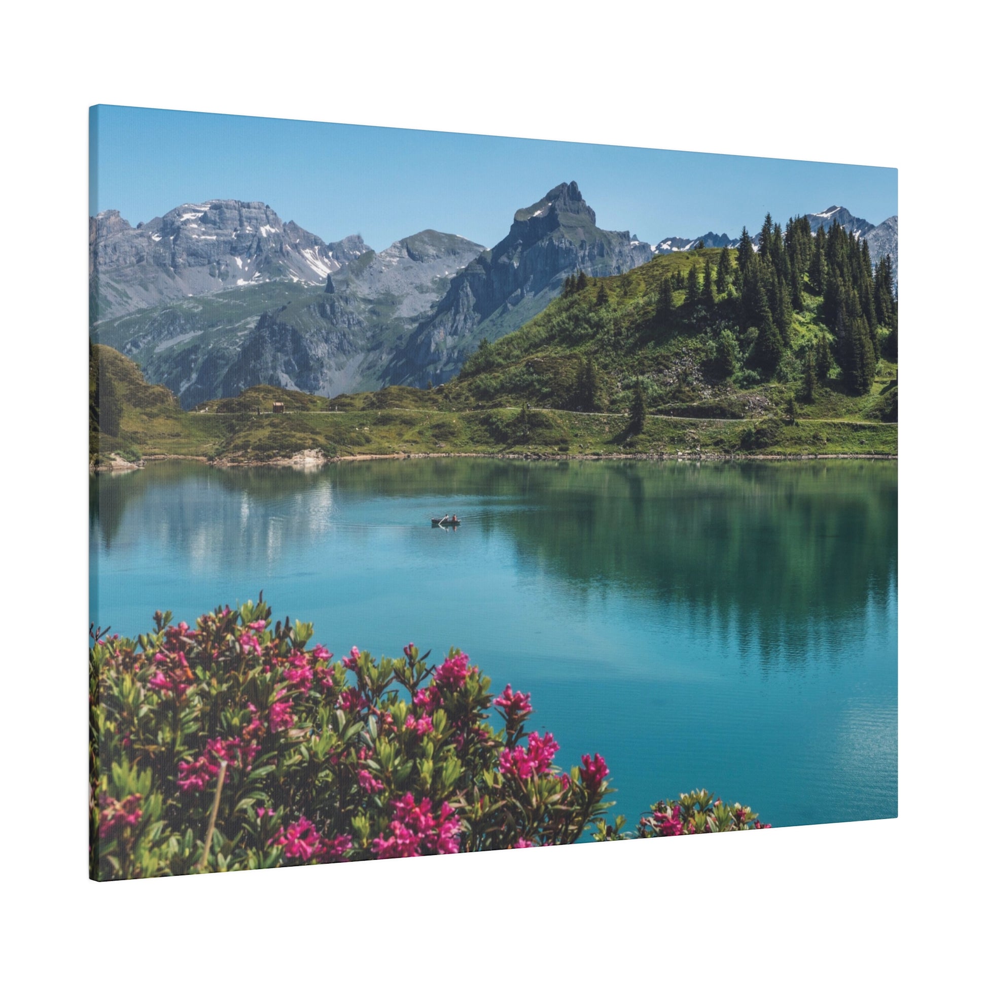 Turquoise lake reflects green hills, pine trees, and snow-capped mountains, with pink flowers in the foreground.
