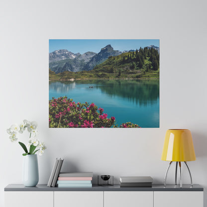 Square wall art of a mountain lake scene with turquoise water, green hills, and pink flowers in the foreground.