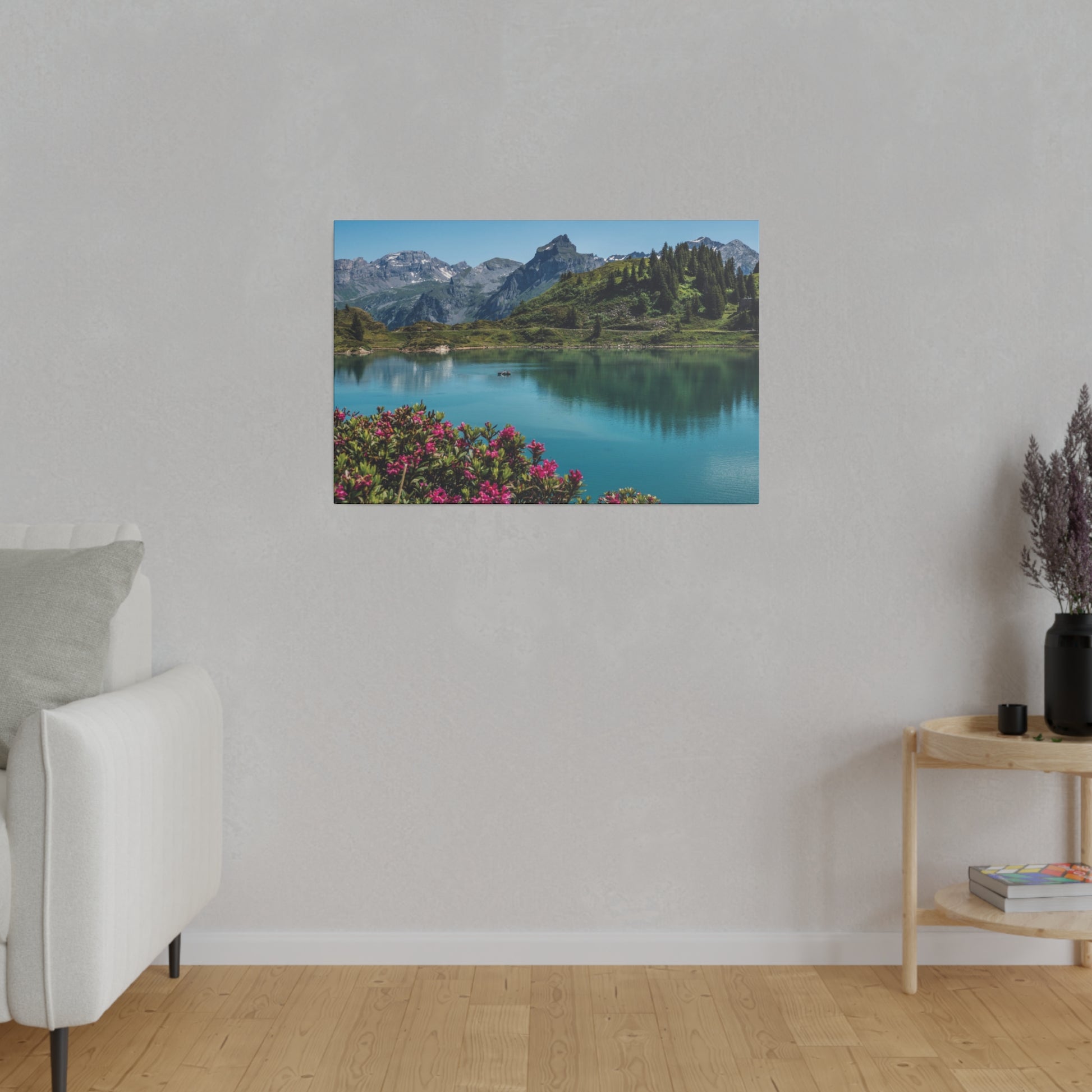 Rectangular wall art showing a blue alpine lake with green hills and mountains in the background, pink flowers in the foreground.