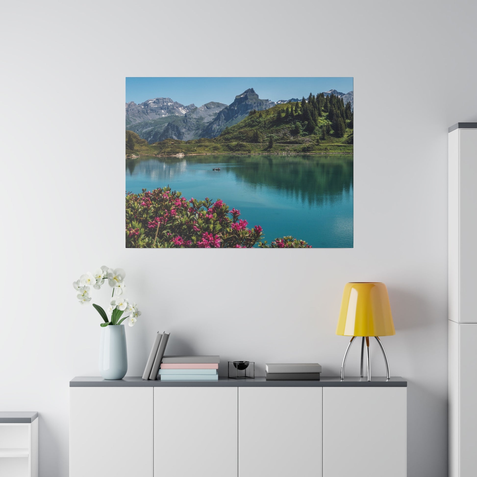 Alpine landscape photo: turquoise lake, green hills, snow-capped mountains, and pink flowers in the foreground.