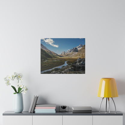 Photo of a mountain valley with a winding river, snow-capped peaks, hung on a white wall.
