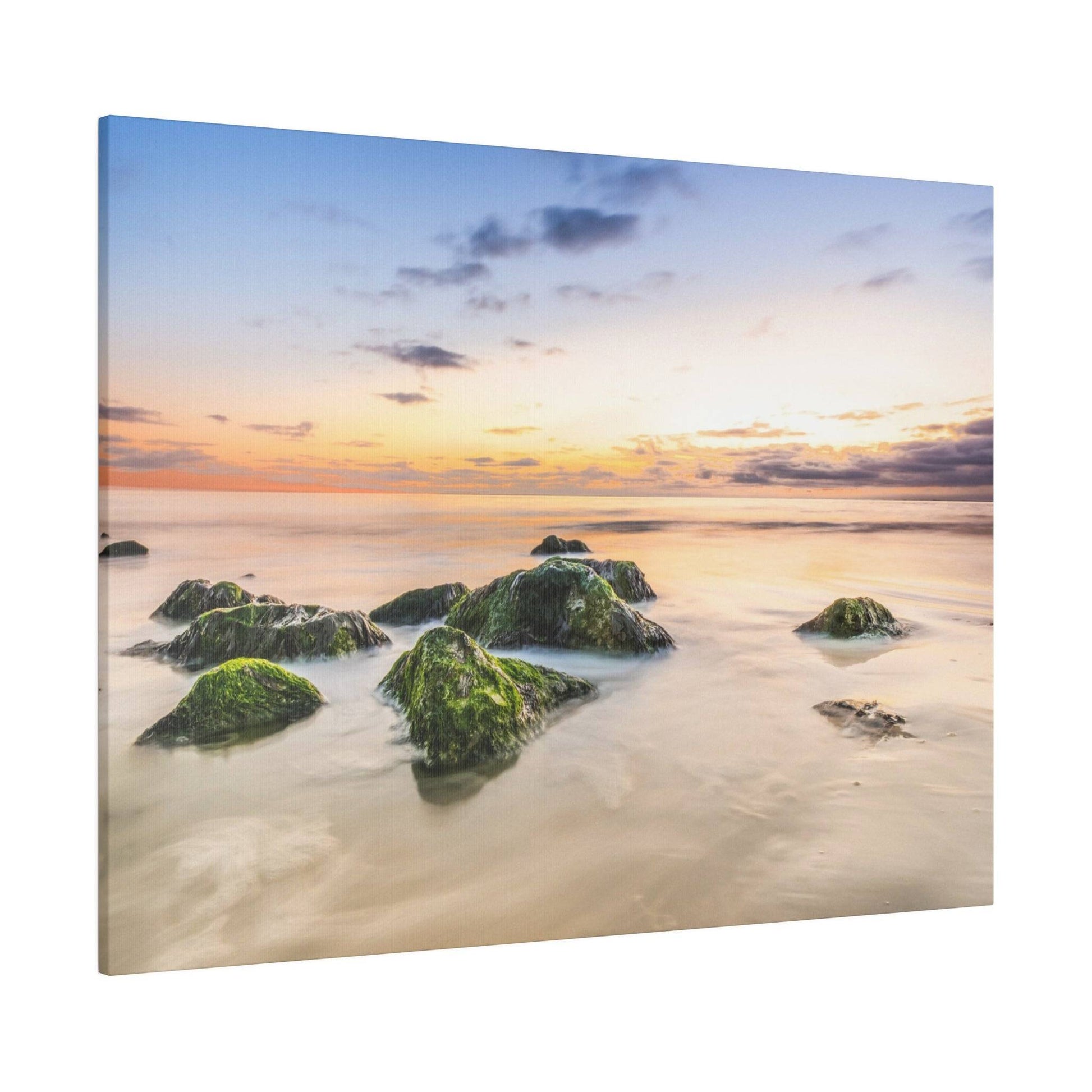 Rocks covered in green moss sticking up through shallow, smooth water at sunset.
